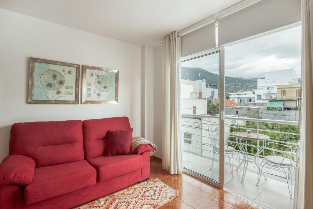 a living room with a red couch and a large window at Apto Yurena 10B 2B in Los Llanos de Aridane