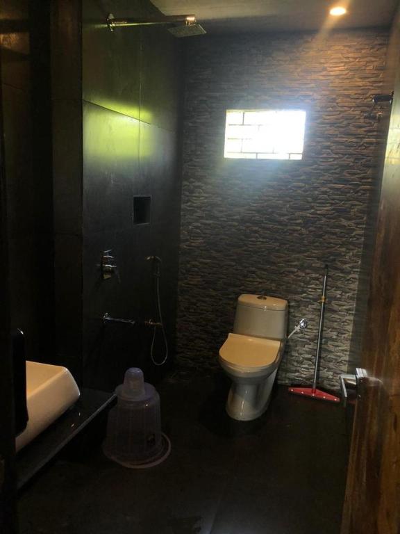 a bathroom with a toilet and a sink and a window at Aariv Inn BAGA BEACH in Baga