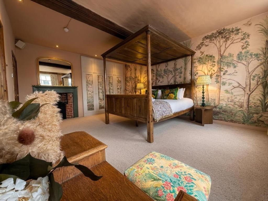 a bedroom with a canopy bed and a fireplace at The Great House Lavenham Hotel & Restaurant in Lavenham
