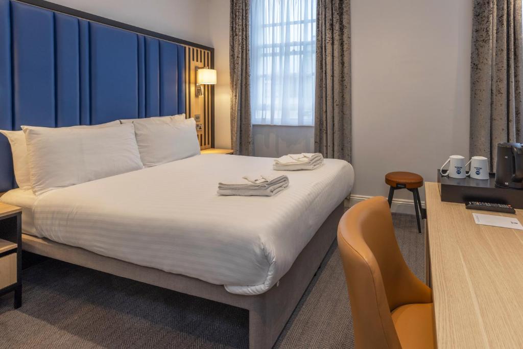 a hotel room with a bed and a chair at Best Western Victoria Palace in London