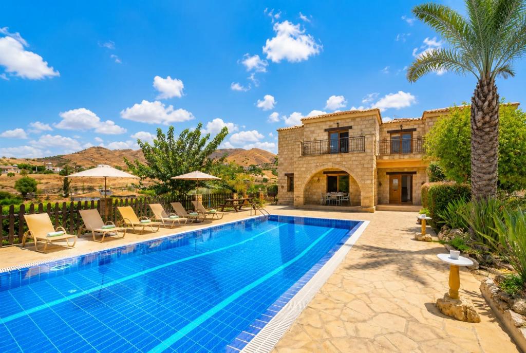a villa with a swimming pool and palm trees at Villa Androulla in Argaka