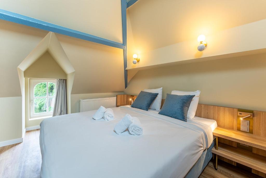 a bedroom with a large white bed with blue pillows at Hotel 't Putje in Bruges