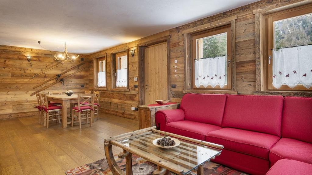 a living room with a red couch and a table at Chalet Sozzine in Ponte di Legno