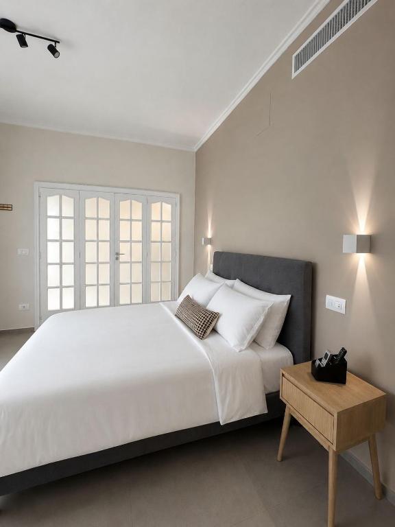 a white bedroom with a large bed and a table at VK Rooms in Bari