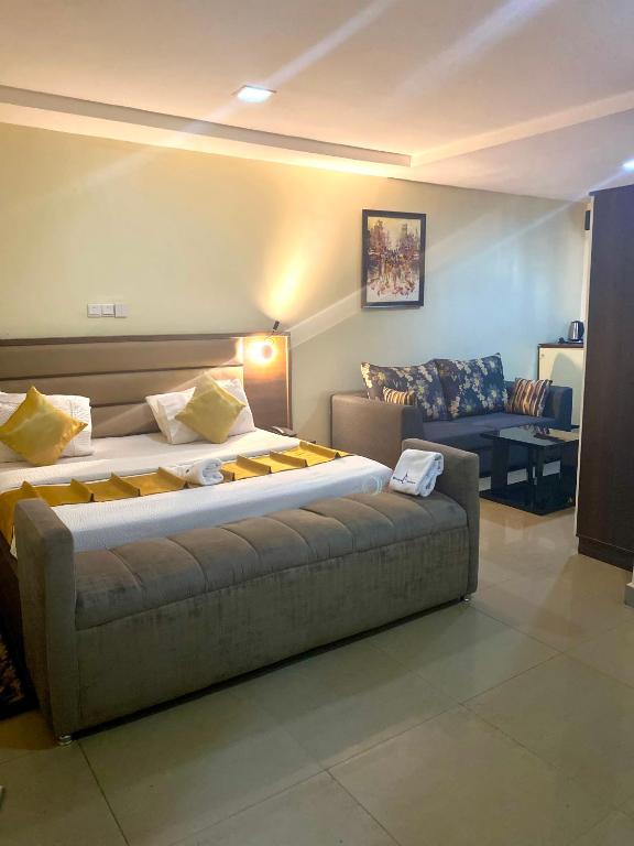 a bedroom with a large bed and a couch at Bridgewaters Hotel in Abuja