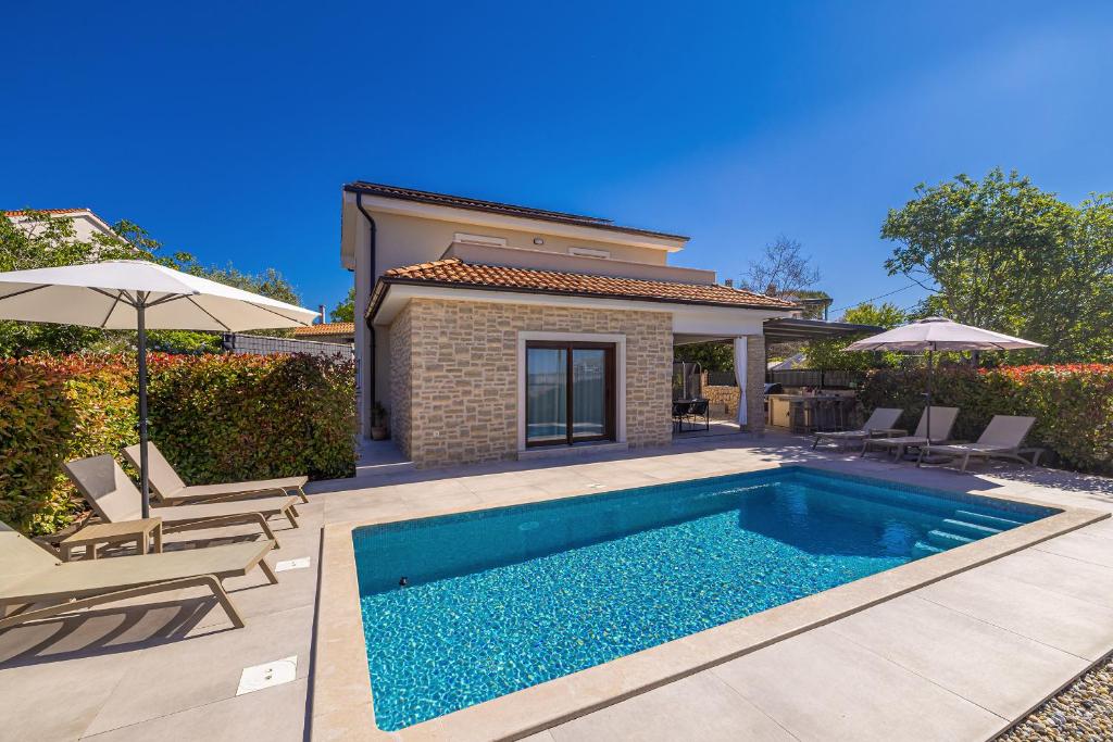 a swimming pool in front of a house at Holiday house VILLA ANDRO in Pinezici