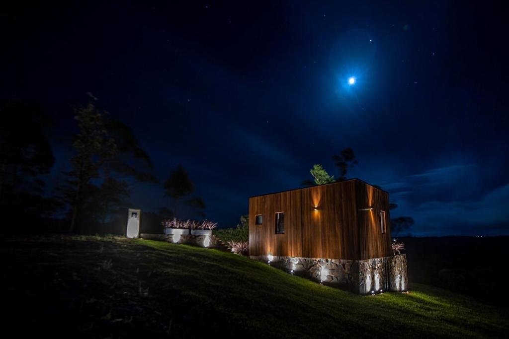 a small wooden house on a hill at night at Studio Sunrise - Luxo, Romance e Natureza in Rancho Queimado