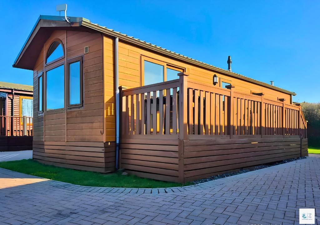 a small wooden house with a fence on a driveway at Rupert's Lodge in West Down