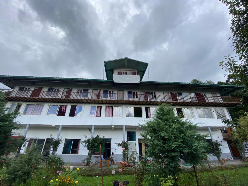 a large white building with a green roof at Hotel Chandra Paradise in Munsyari