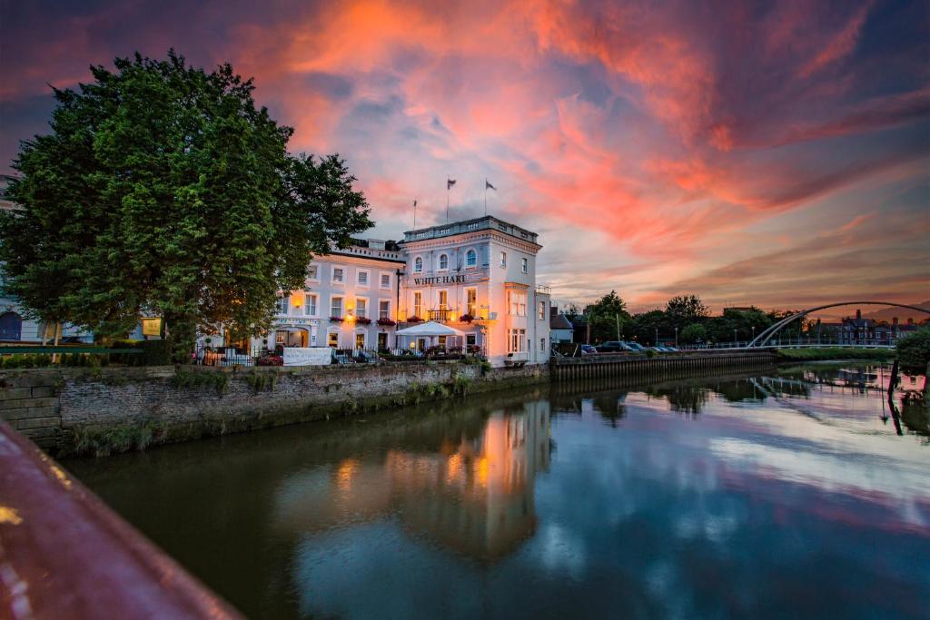 a building in front of a river with a sunset at The White Hart Hotel, Boston, Lincolnshire - The Coaching Inn Group in Boston