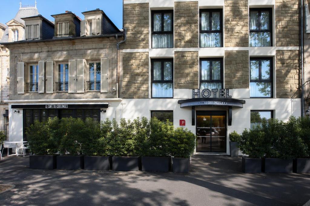 a building with bushes in front of it at Hôtel Le Collonges in Brive-la-Gaillarde