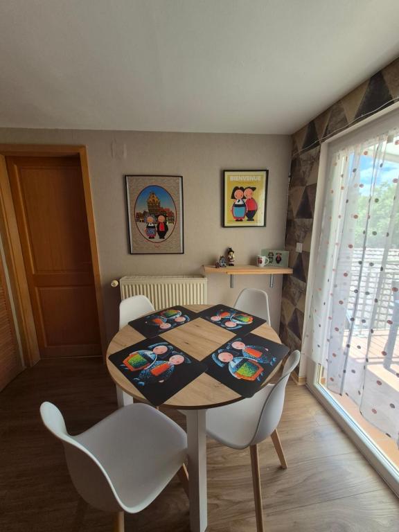 a dining room with a table and white chairs at Le repaire des 6 Manalas in Ingersheim