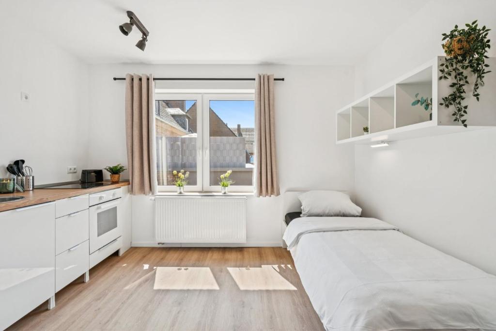 a white bedroom with two beds and a window at Boardinghouse Rees in Rees