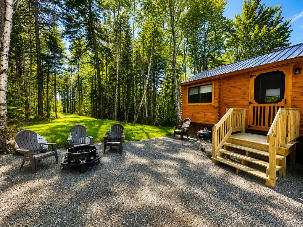 a log cabin with chairs and a table and a grill at Cozy Coastal Cabin 5 in Steuben