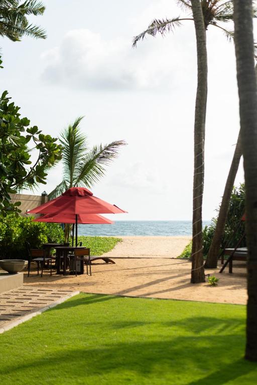 a table with a red umbrella on the beach at Ayuda Sanctuary Boutique Negombo in Negombo
