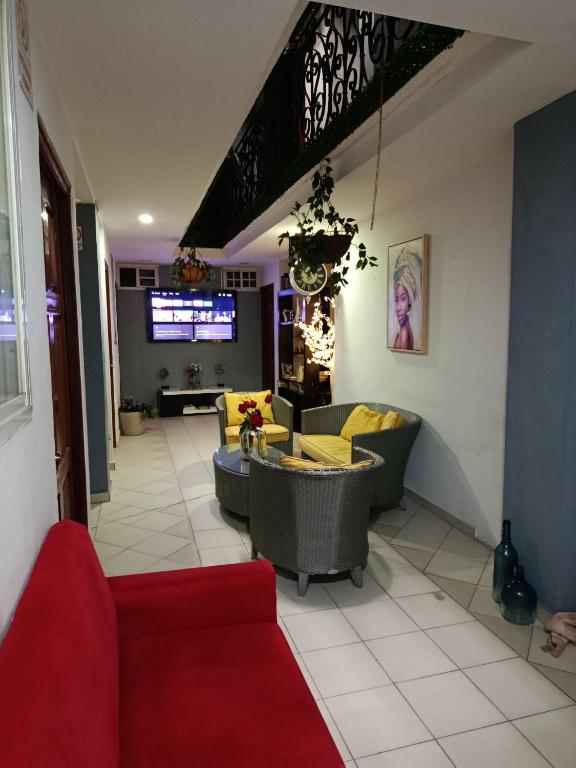 a living room with a red couch and yellow chairs at Hostal Cigarra in Panama City