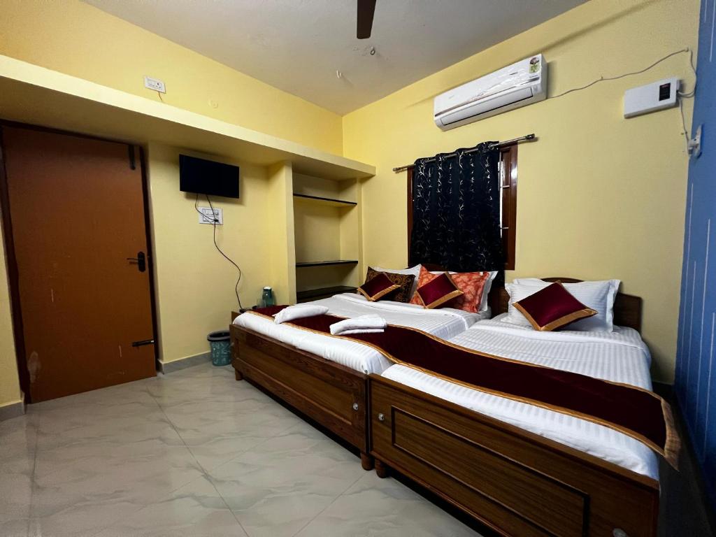ein Schlafzimmer mit zwei Betten und einem Fernseher und einer Tür in der Unterkunft Rivera inn in Tiruchirappalli