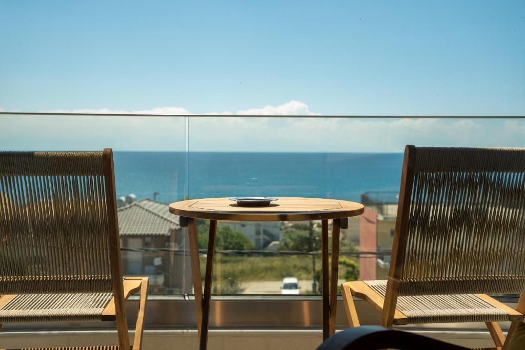 a table and two chairs on a balcony with a view at Evi Seaside Suites in Kanali
