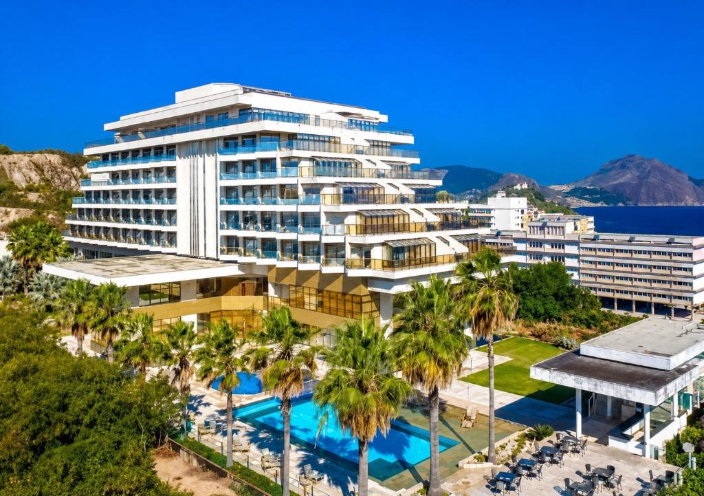 a large building with a pool and palm trees at Apartamento Vista Jardim in São Domingos