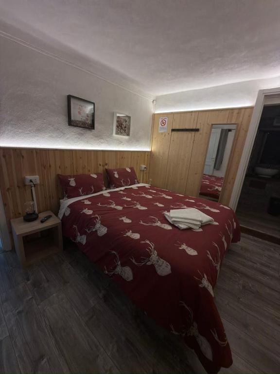 a bedroom with a bed with a red comforter at La ca veja in Locana