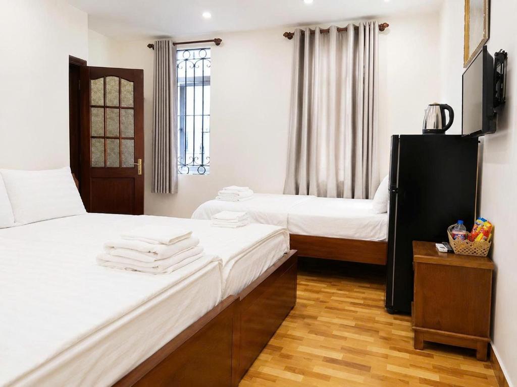a room with two beds with white sheets and a table at KS Phương Danh in Quy Nhon