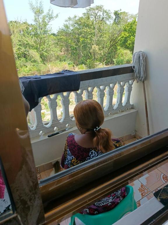 a young girl sitting on a balcony looking out the window at Bafadhil vacation home in Kilifi