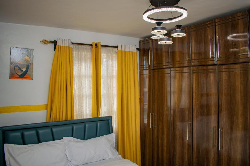 a bedroom with a bed with yellow curtains and a chandelier at executive home in Eldoret