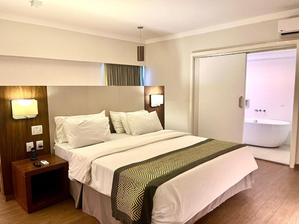 a hotel room with a large bed and a bathroom at Oasis Plaza Hotel in Ribeirão Preto