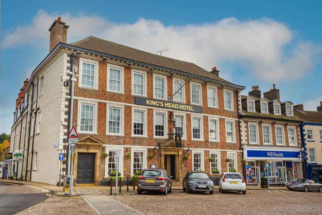 a large brick building with cars parked in front of it at The Kings Head Hotel, Richmond, North Yorkshire - The Coaching Inn Group in Richmond