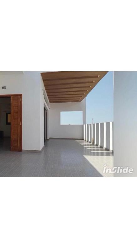 an empty room with a white wall and a wooden ceiling at la perle de ngaparou in Saly Portudal