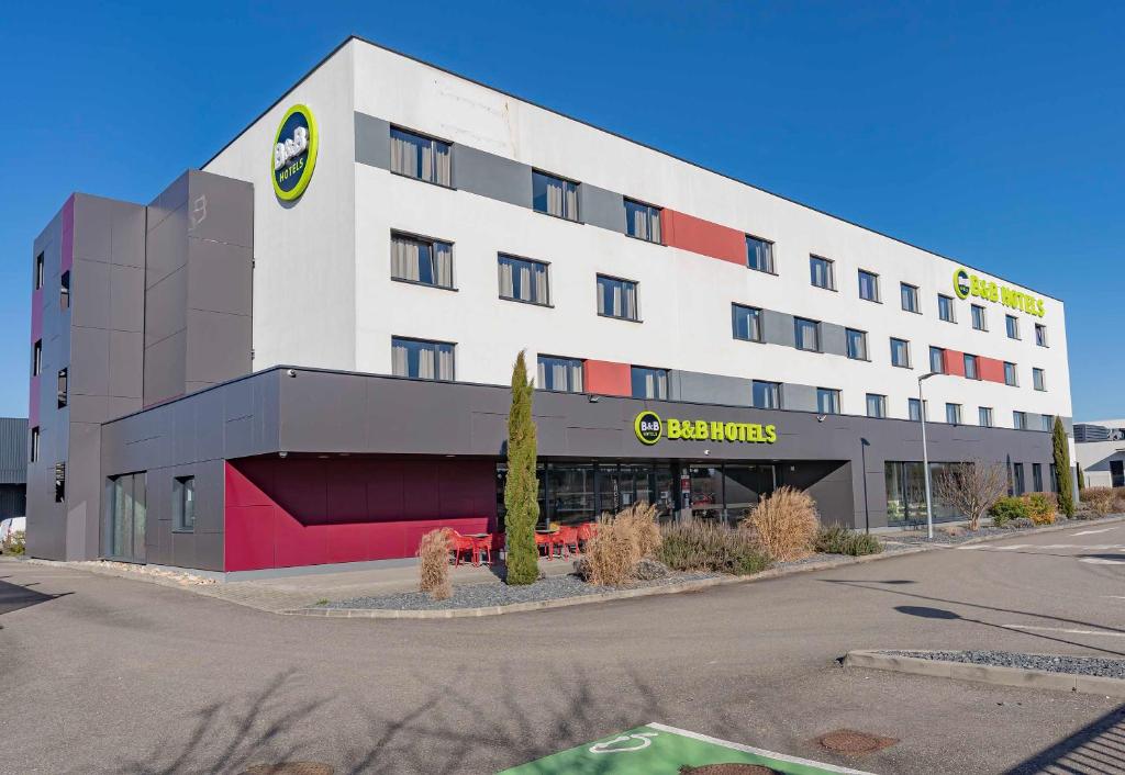 a large white building with a bahawks sign on it at B&B HOTEL Brumath Bernolsheim in Brumath