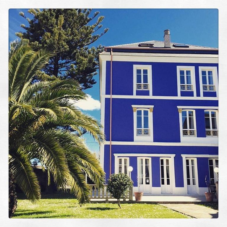 a purple house with a palm tree in front of it at Hotel La Balastrera in Ribadeo