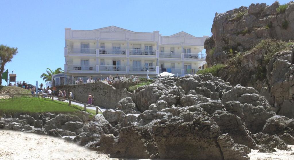 a large building on the side of a cliff at Hotel Pineda Playa in Noja