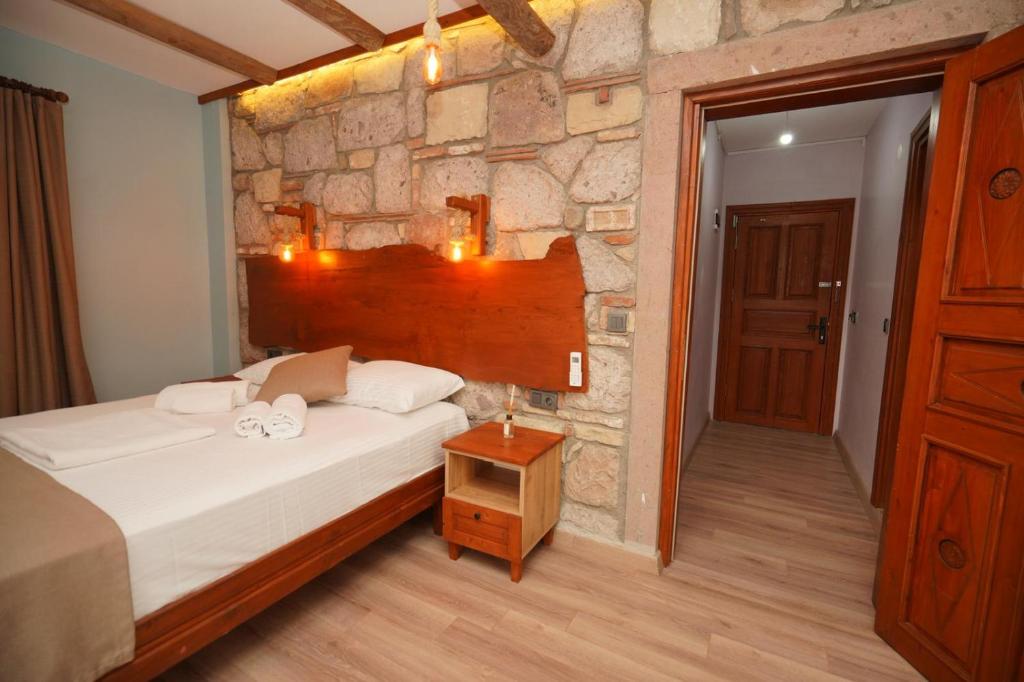a bedroom with a bed and a stone wall at Lotus Konaklama Küçükköy in Ayvalık