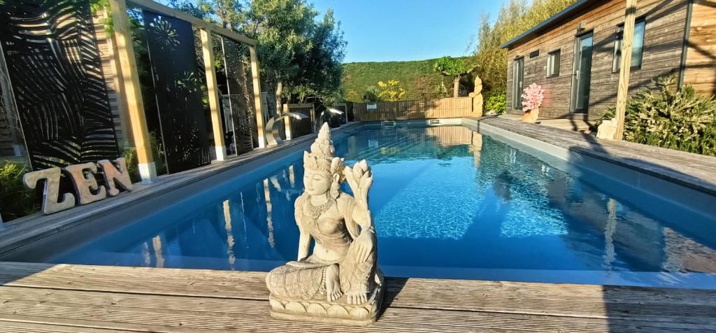 a statue sitting on a deck next to a swimming pool at Cocoon inn&Spa in Saint-Saturnin-les-Avignon