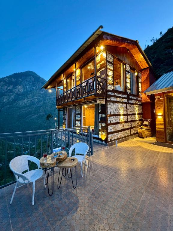 a house with a table and chairs on a patio at Tirthan Chalet in Kulu
