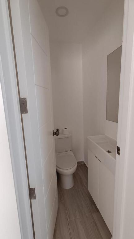 a white bathroom with a toilet and a sink at One suite los corales in Punta Cana