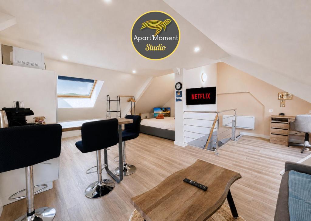 a attic room with a bed and a room with a table at Studio spacieux et élégant au cœur de Bourbourg - gare à proximité in Bourbourg
