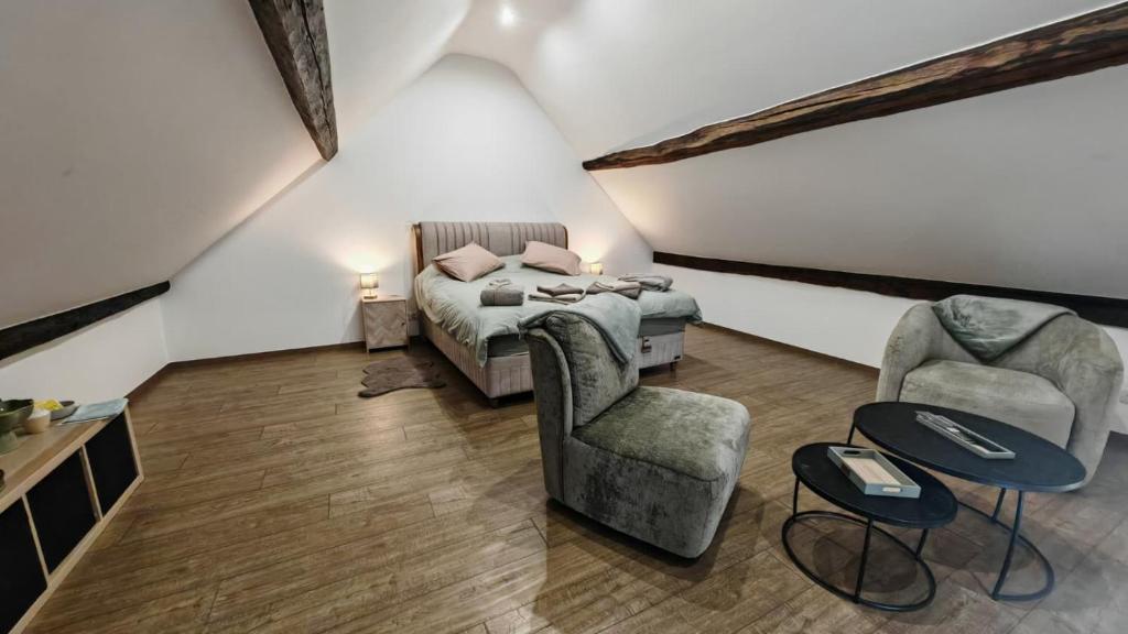 a bedroom with a bed and two chairs at La Petite Auberge de Graux in Mettet