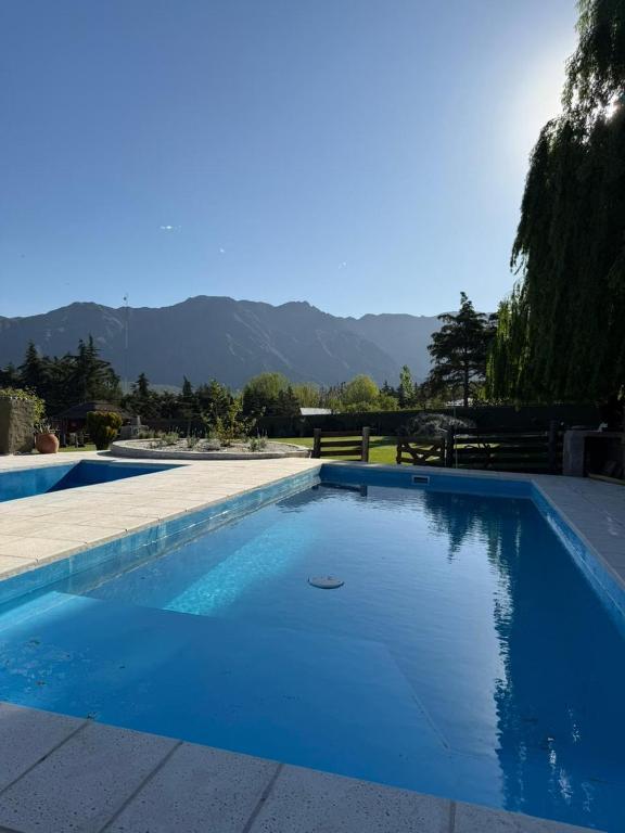 a blue swimming pool with mountains in the background at Cabaña Suiza in Cacheuta