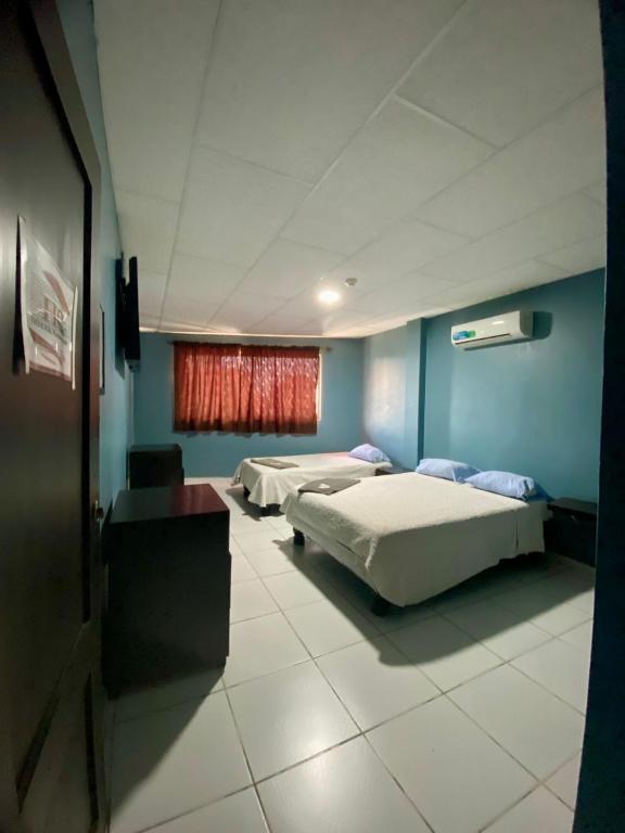 a room with two beds and a window at Hotel Confort in Guayaquil