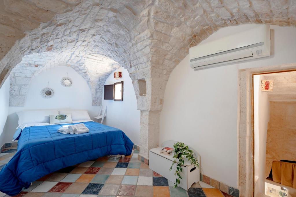 a bedroom with a blue bed in a stone wall at Domus Magistri in Ostuni