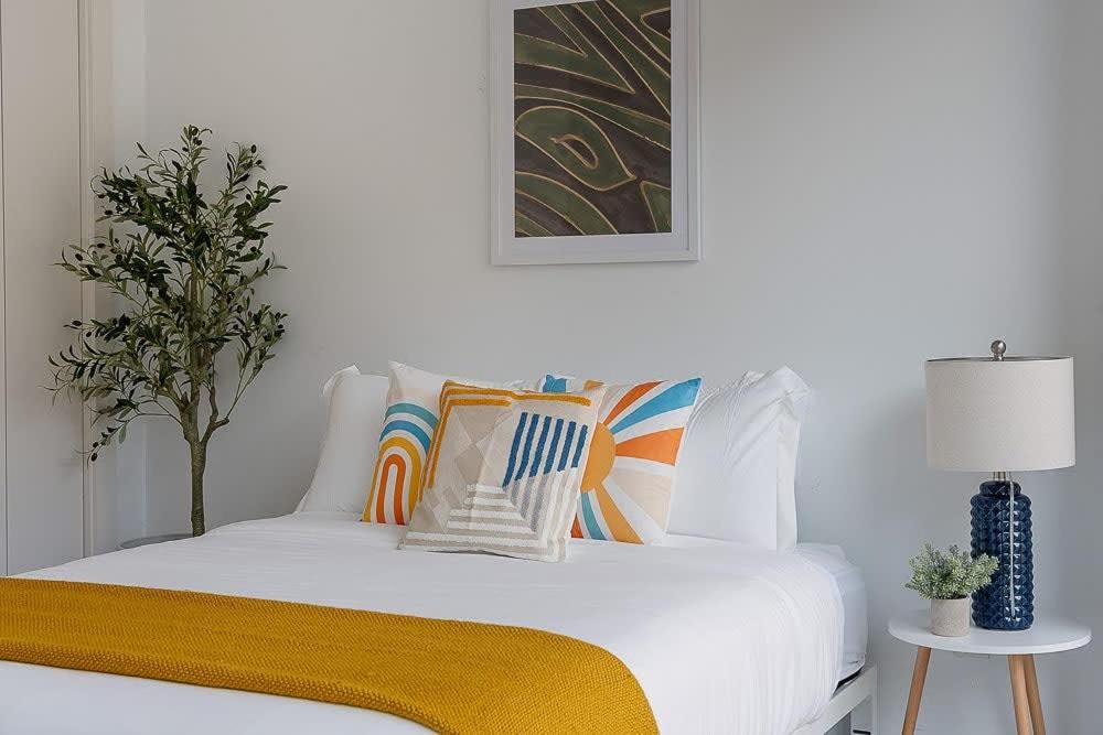 a bedroom with a white bed with a yellow blanket on it at South Downtown Condo no.308 in Dallas