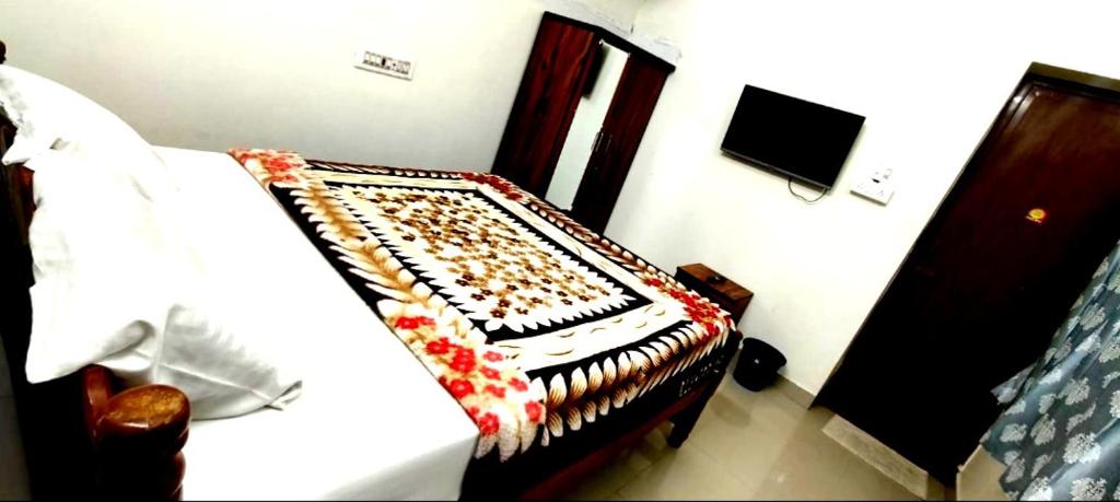 a bedroom with a bed and a tv on the wall at ANS Green Villa in Yercaud