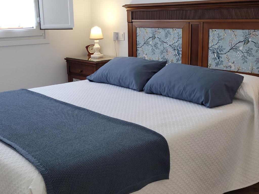 a bed with two blue pillows on top of it at Vaniria 4 Apartamentos Nuevos in Foz