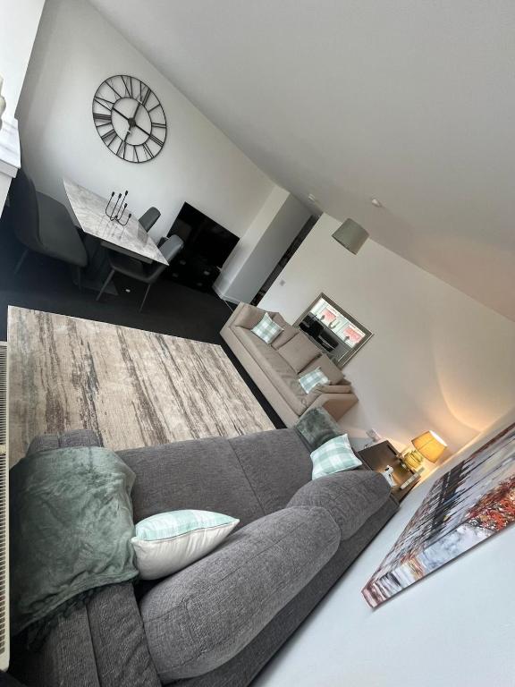 a living room with a couch and a clock on the wall at The M Rooms at 144 in Kirk of Shotts