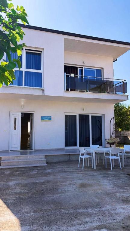 a white house with a table and chairs in front of it at Vila 007 in Velipojë