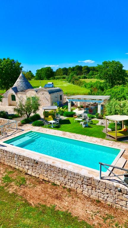 a swimming pool in a yard with a stone wall at Trulli Paradise Alberobello in Alberobello