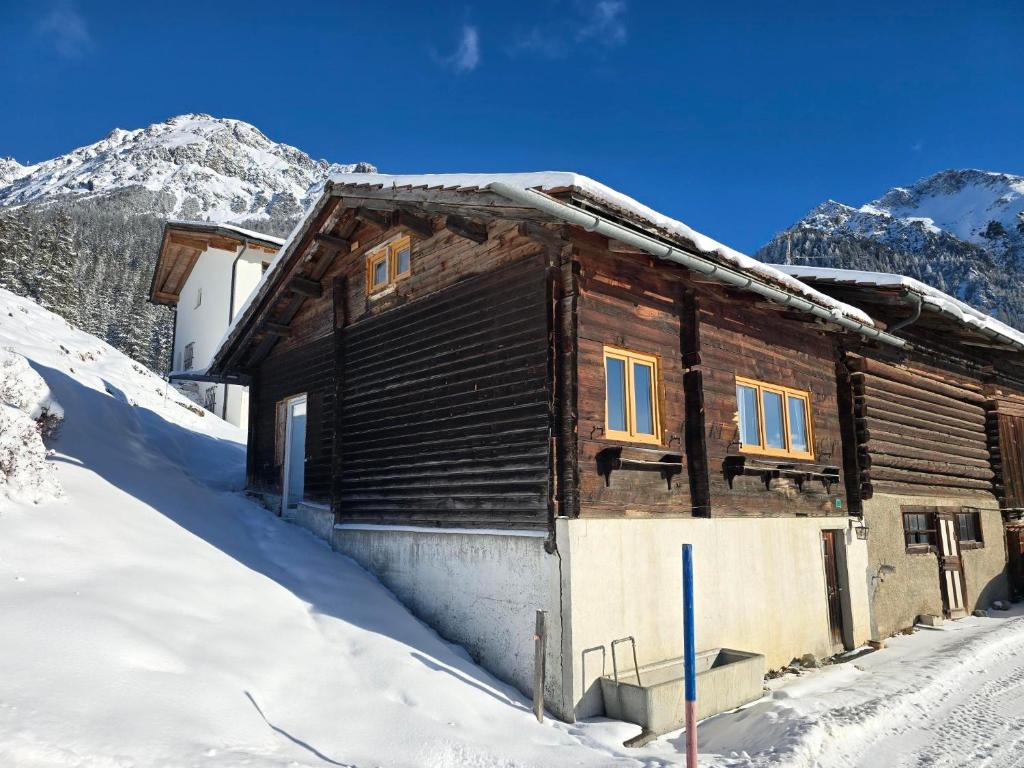 a wooden cabin in the snow with mountains in the background at Maiensäss Crapera in Lenzerheide