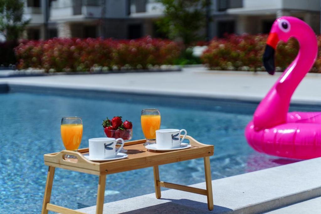 a table with two drinks and a pink swan chair at Apartments with Pool 5 Min Walk to Beach in Igalo